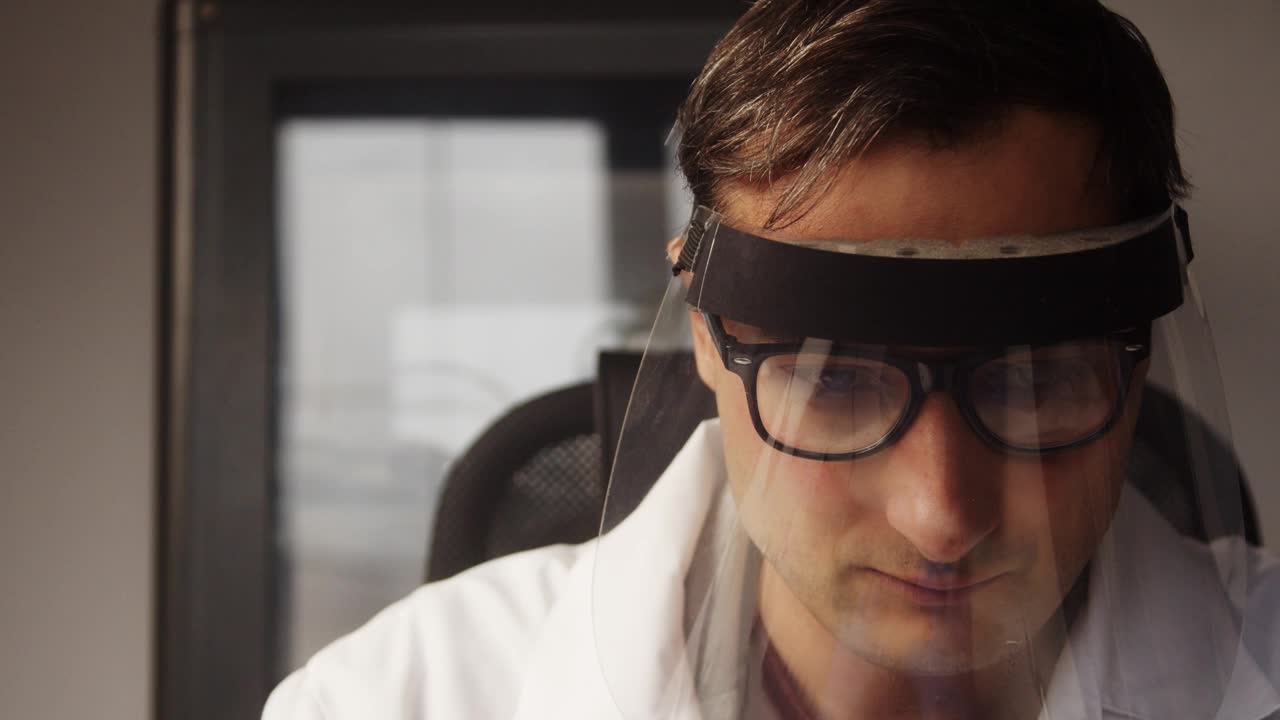 一位疲惫的实验室技术人员摘下防护口罩和护目镜视频下载