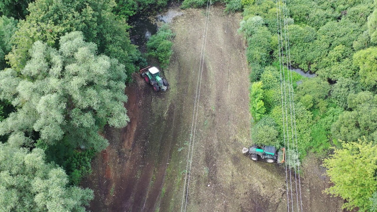 两辆拖拉机正在拆除高压电线下的灌木丛视频下载