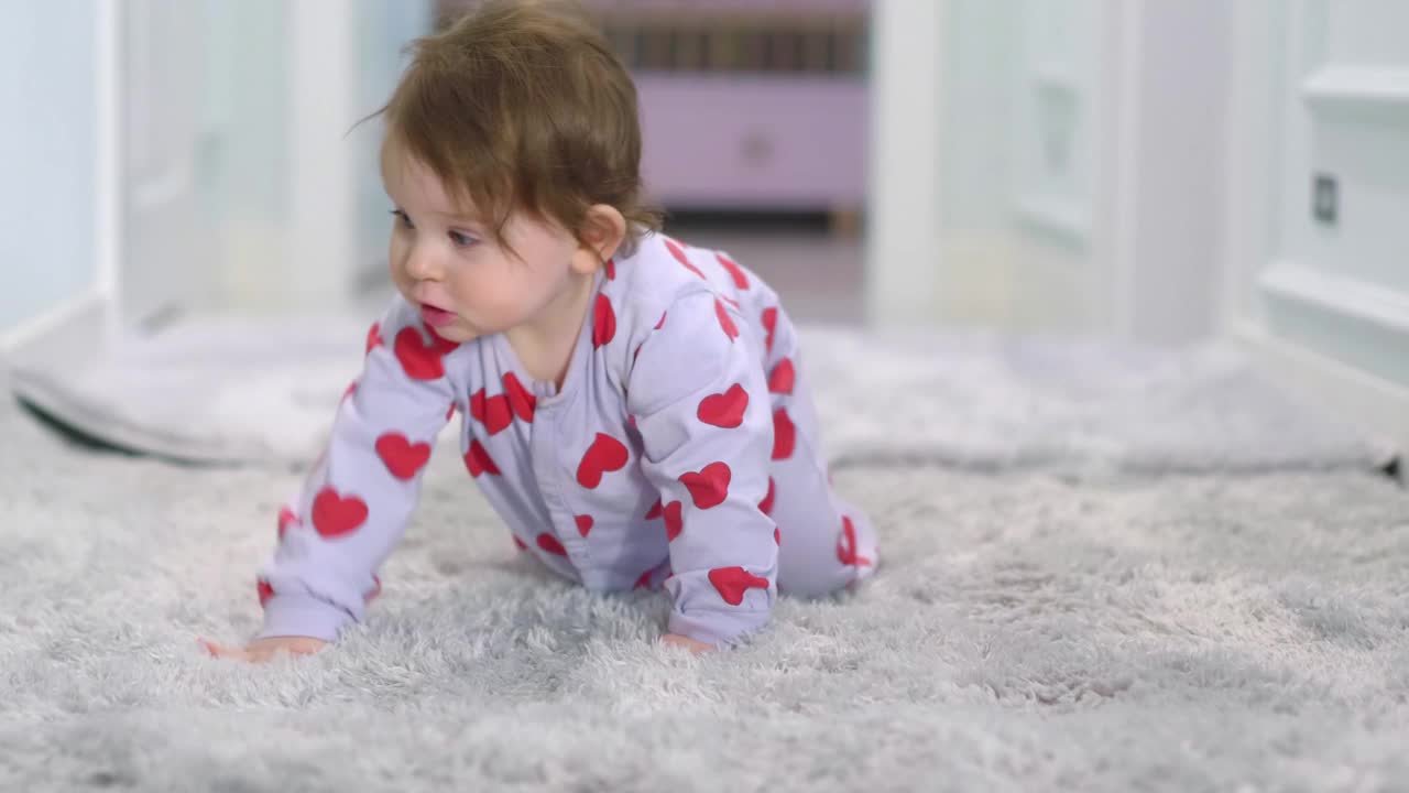 一个穿着心形连体衣的婴儿在柔软的地毯上爬行，4k慢动作，每秒60帧视频下载