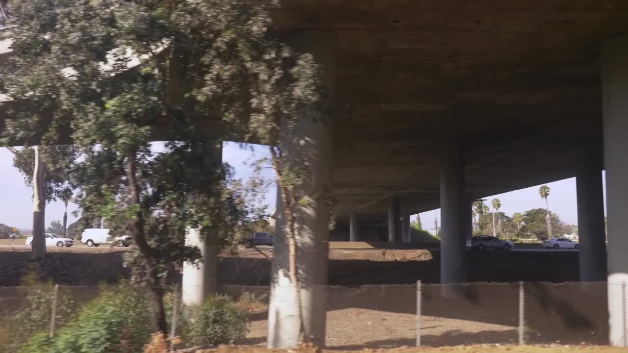 在繁忙的高速公路旁，通过茂密的树木的加州风景，4k慢动作60fps视频下载