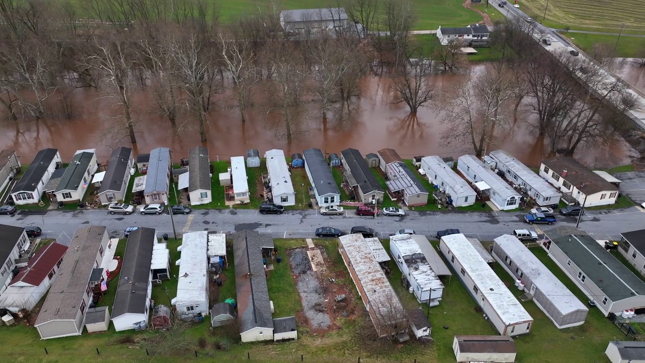 被洪水淹没的河流旁的拖车停车场。暴雨过后，低收入住房被淹没在河床上。空中卡车在移动房屋上方拍摄。视频下载