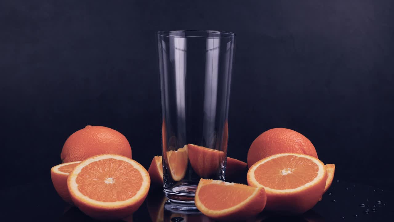 新鲜的橙汁倒进黑色背景的杯子里视频下载