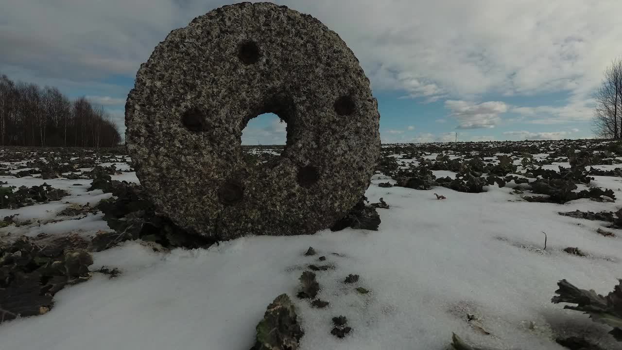 历史上的石磨在春田上随着雪花和云彩移动，时光流逝视频下载