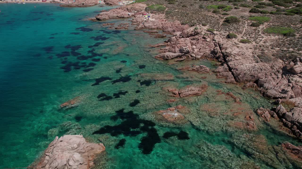 空中侧向拍摄的岩石海岸线和人们游泳在马达莱纳岛撒丁岛意大利视频下载