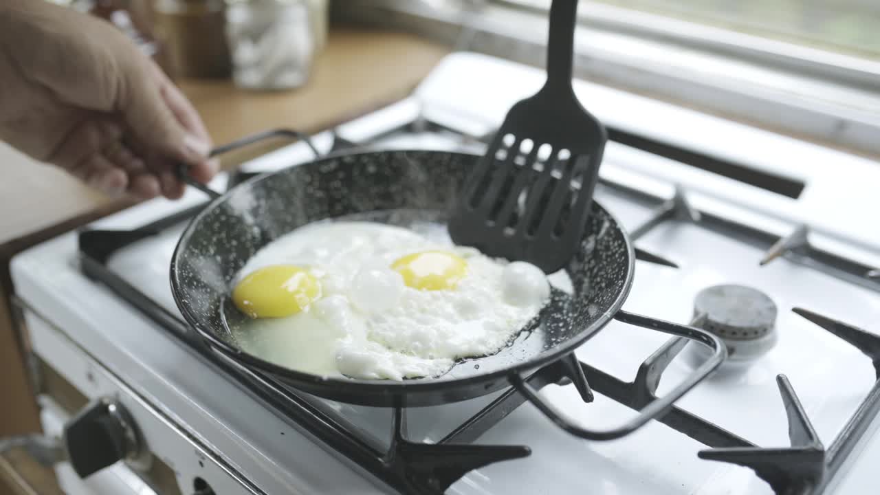 人，做饭和厨房用鸡蛋，炉子和锅铲在家里，准备和食物。早餐，单面煎，煎锅加蛋白质，早上加生肉和菜板，手和饭视频下载