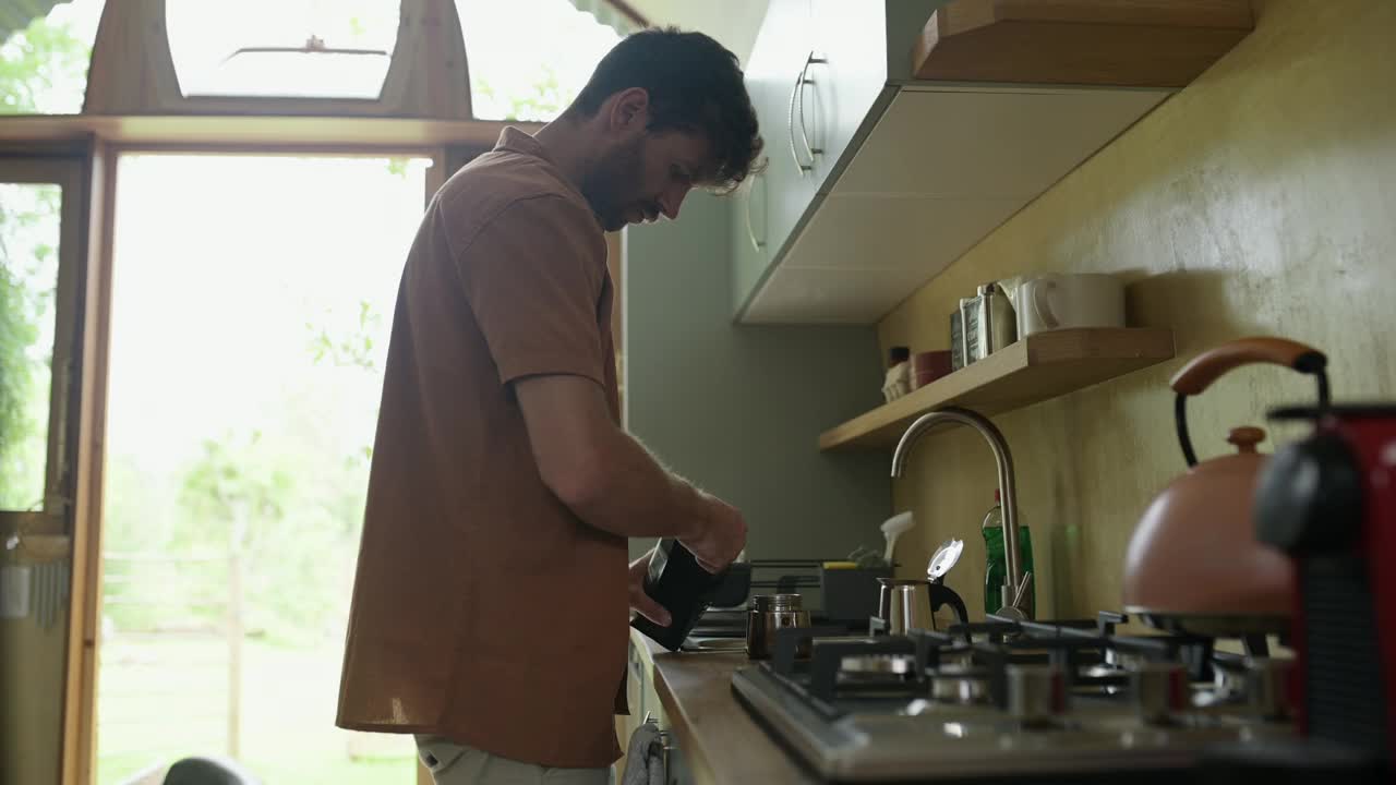 男士，在水壶里准备咖啡和浓缩咖啡，或者早上在厨房里喝卡布奇诺，冲泡或拿铁。男性，在公寓里有壶和热水或咖啡因设备，用于取暖、饮料或早午餐视频下载