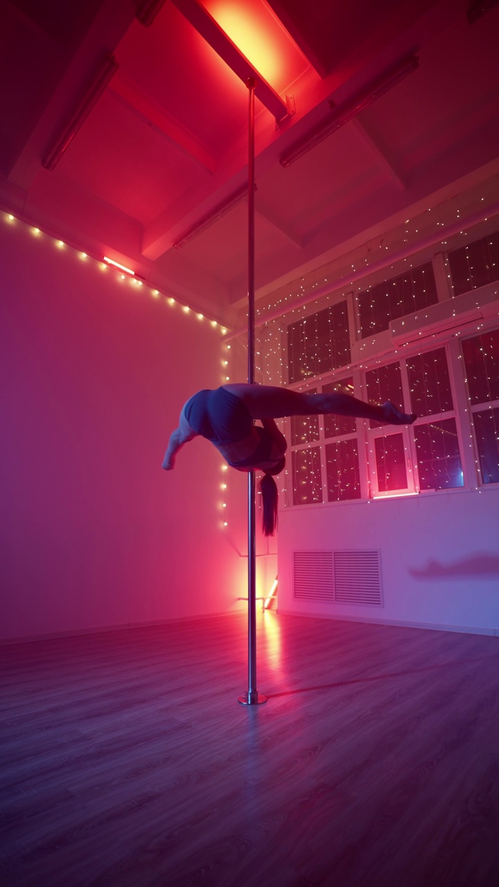 优雅的女子在霓虹灯下跳钢管舞。垂直视频视频下载