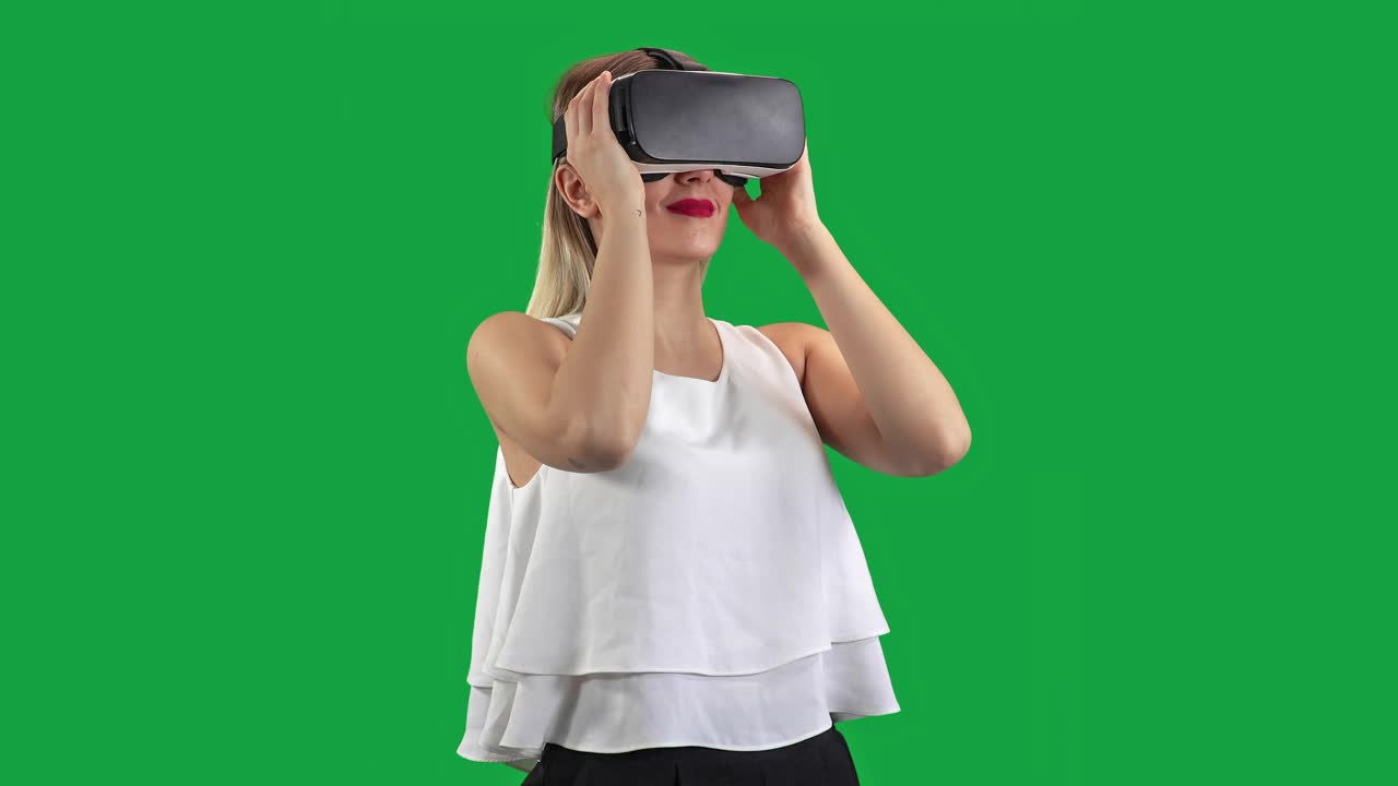 绿色屏幕上戴着虚拟现实眼镜的漂亮女孩。4 k视频下载