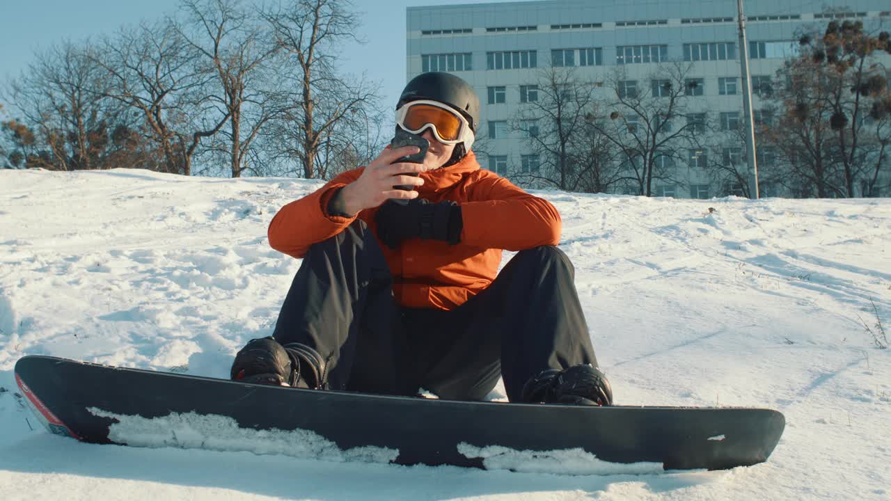 戴着滑雪护目镜的男子一边滑雪一边看手机视频下载