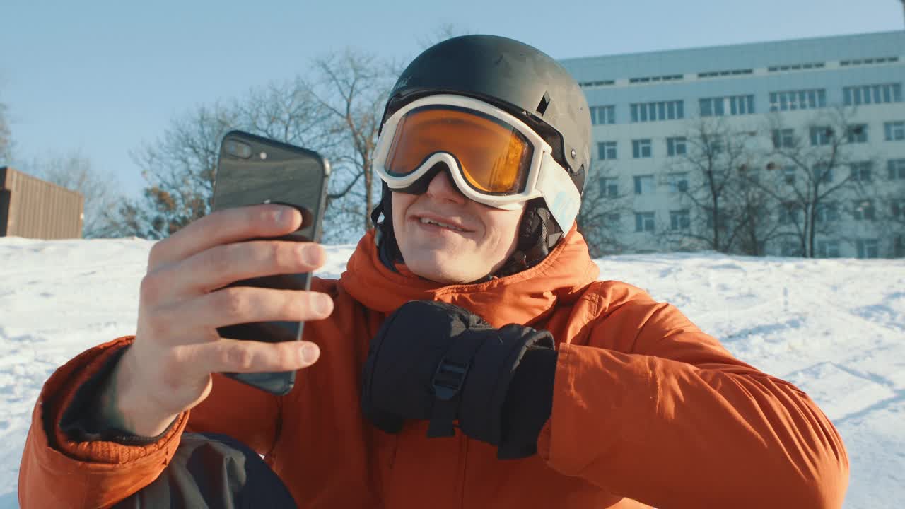 戴着滑雪护目镜的男子一边滑雪一边看手机视频下载