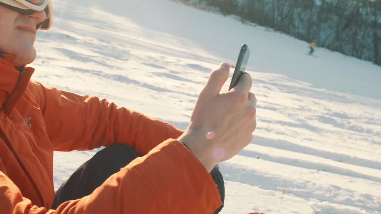 戴着滑雪护目镜，一边用智能手机打字一边滑雪的特写镜头视频下载