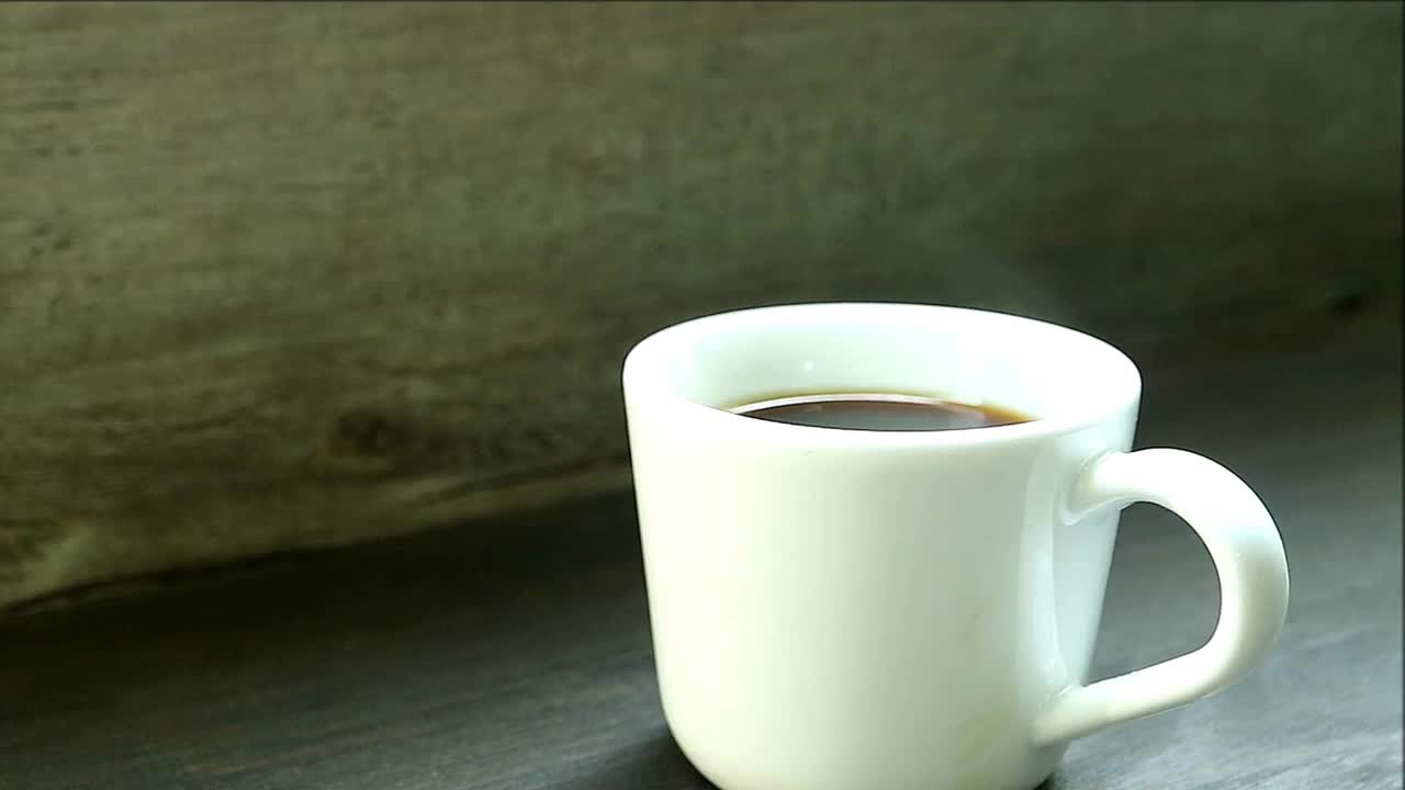 窗边木桌上一杯冒着烟的热咖啡的镜头视频下载
