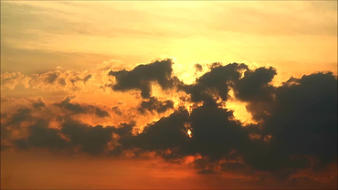 明亮的太阳落在蓬松的云彩在橙色天空的延时镜头视频下载