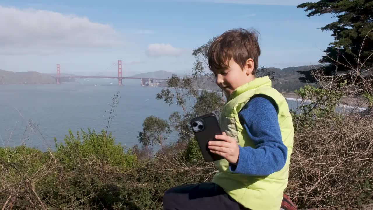小男孩正在用智能手机拍摄旧金山金门大桥视频下载