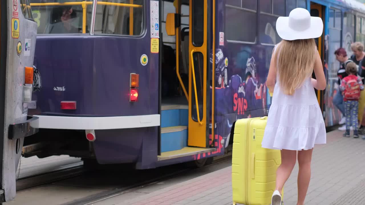 一个女人提着一个大行李朝电车走去。城市道路运输视频下载