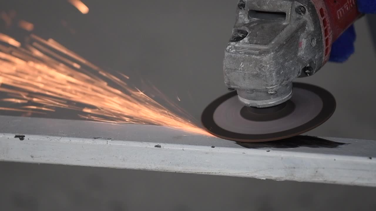 慢动作视频，一个焊工戴着安全手套在磨钢门窗。安全理念与机械工业视频下载
