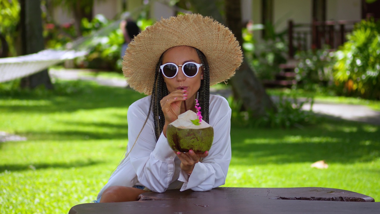 时尚女游客享受热带清凉清凉的夏日假期。戴草帽和太阳镜的女人在热带度假胜地避暑。热带度假概念视频下载