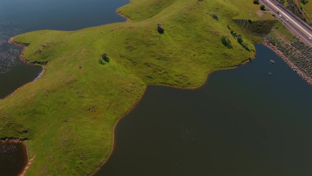 加州默塞德县圣路易斯水库岸边郁郁葱葱的青山。空中倾斜拍摄视频下载