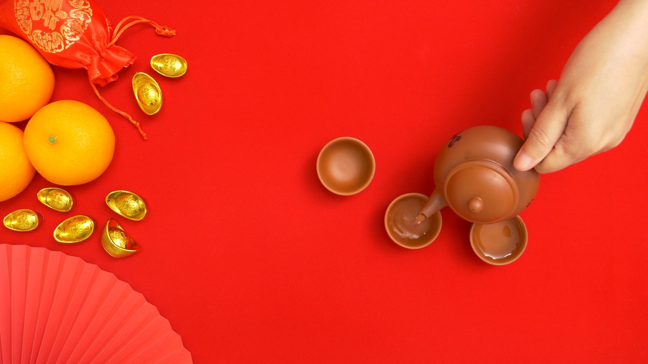 手持式茶壶，将茶倒入茶杯中，有中国农历新年的装饰视频下载