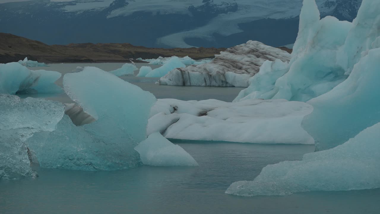 冰岛冰川湖上漂浮的冰川，海鸥在头顶飞过，蓝色的海水向钻石海滩移动视频下载