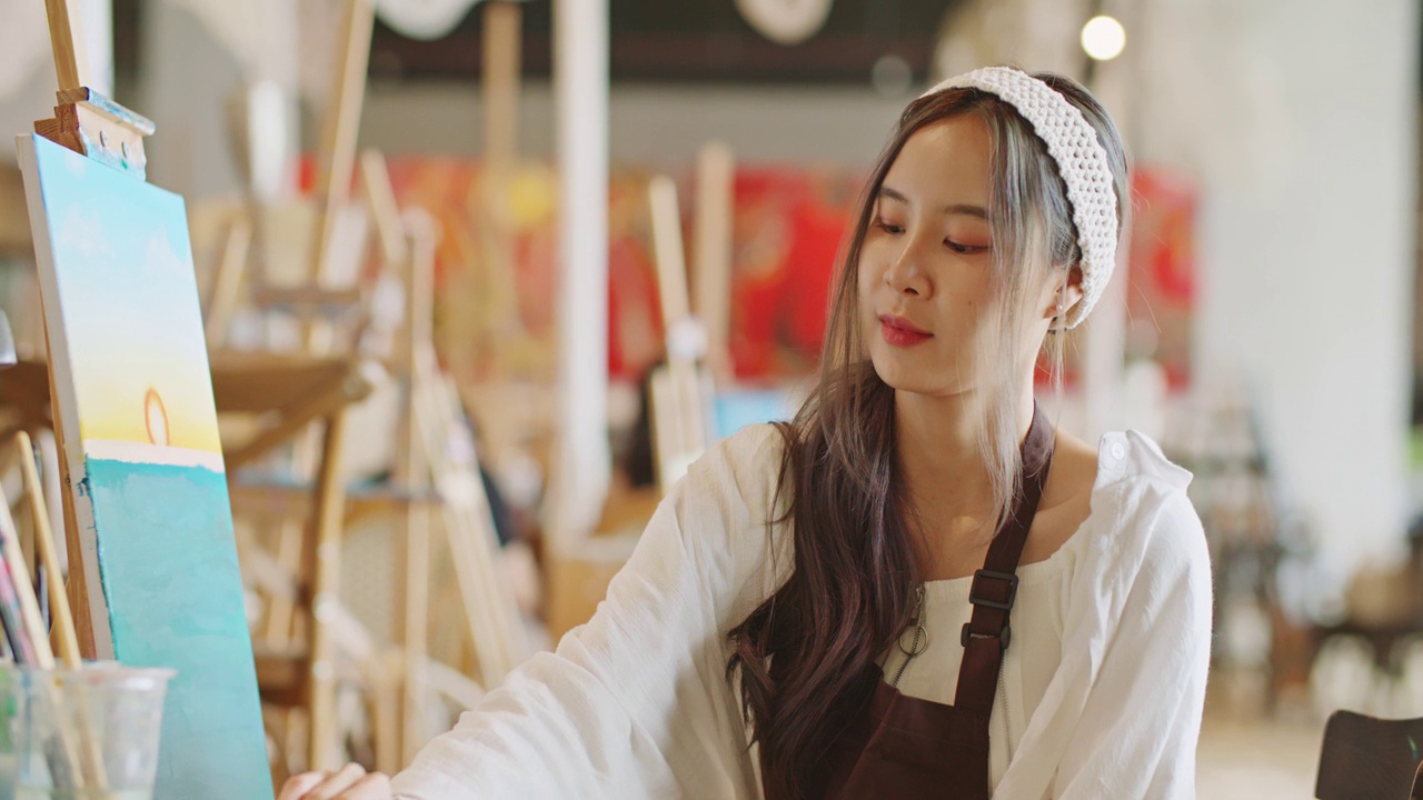 美丽的亚洲女艺术家在艺术工作室看着相机微笑。肖像。视频下载