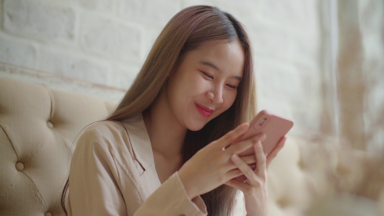 亚洲女性坐在智能手机上发短信、阅读和分享社交媒体。视频下载