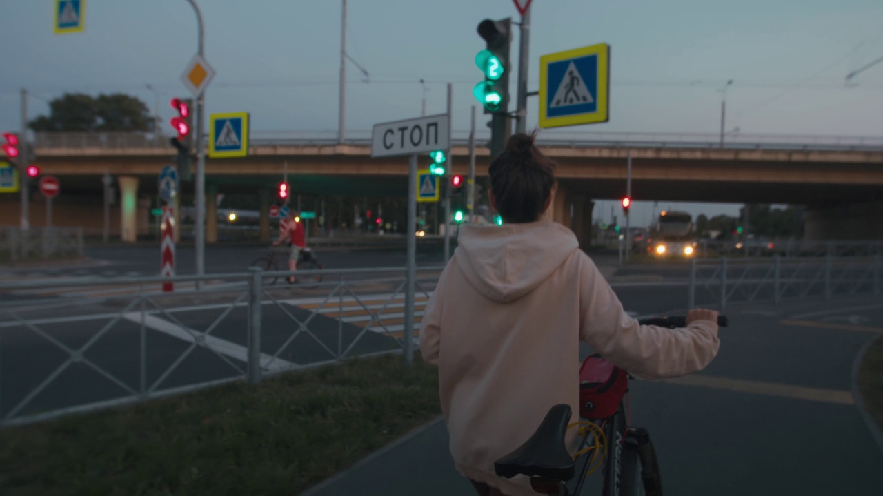 一名女子骑着自行车走在城市的夜巷里视频下载