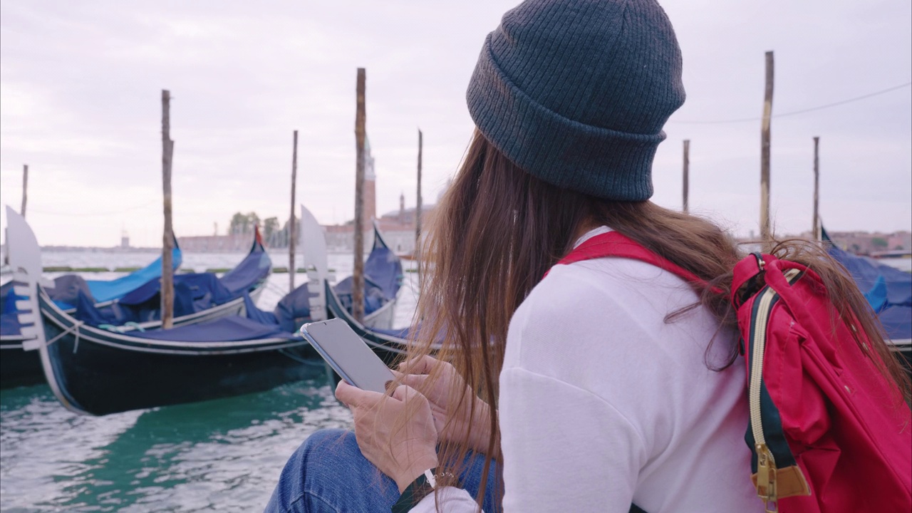 在欧洲的意大利威尼斯，年轻的旅行者用智能手机上的应用程序导航。视频下载