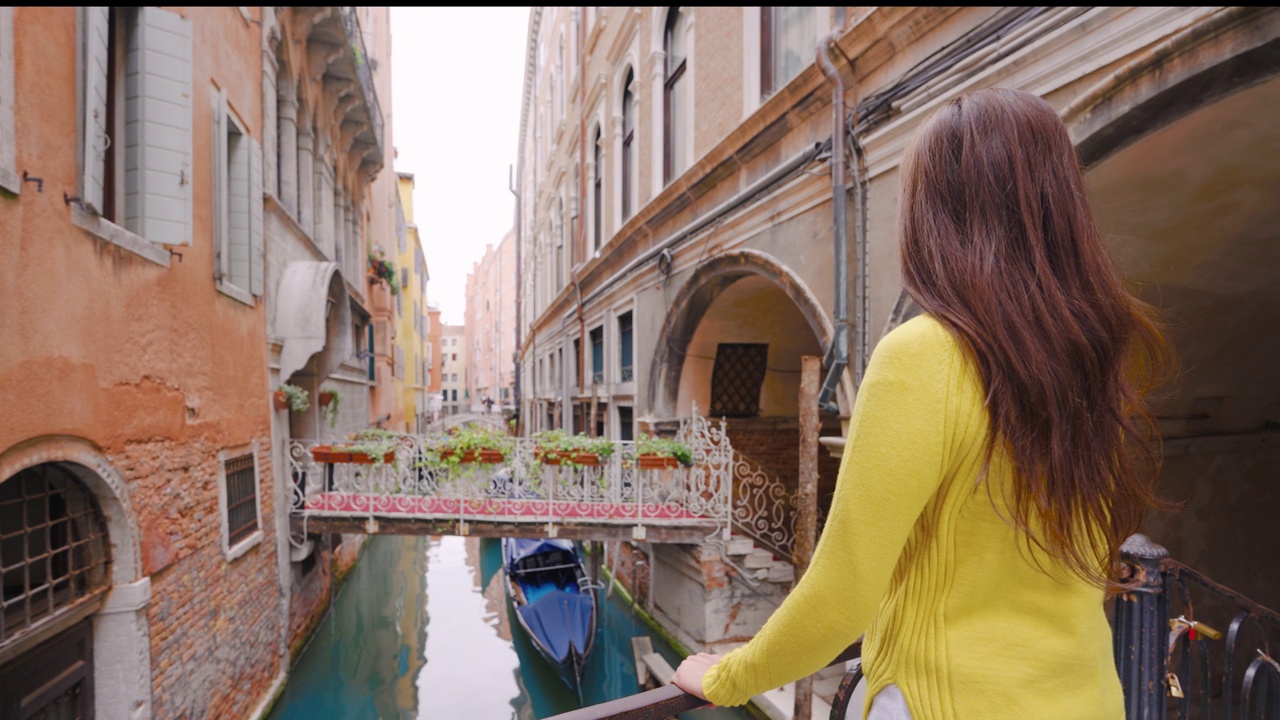 欧洲意大利威尼斯，美丽女孩在桥上欣赏威尼斯运河的背影。视频下载