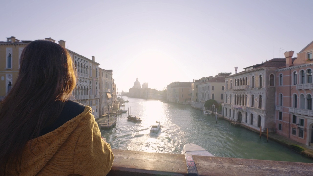 站在欧洲意大利威尼斯桥上的女人的剪影日落。视频下载
