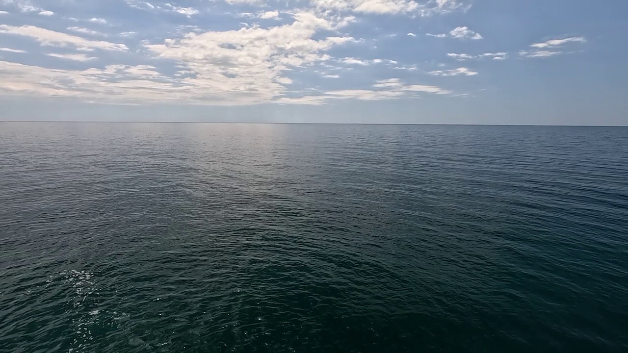 海水表面。在平静的水面上鸟瞰，相机飞过清澈的海洋。太阳眩光。抽象航海夏季海洋自然。假期和旅行。天气和气候变化。慢动作视频下载