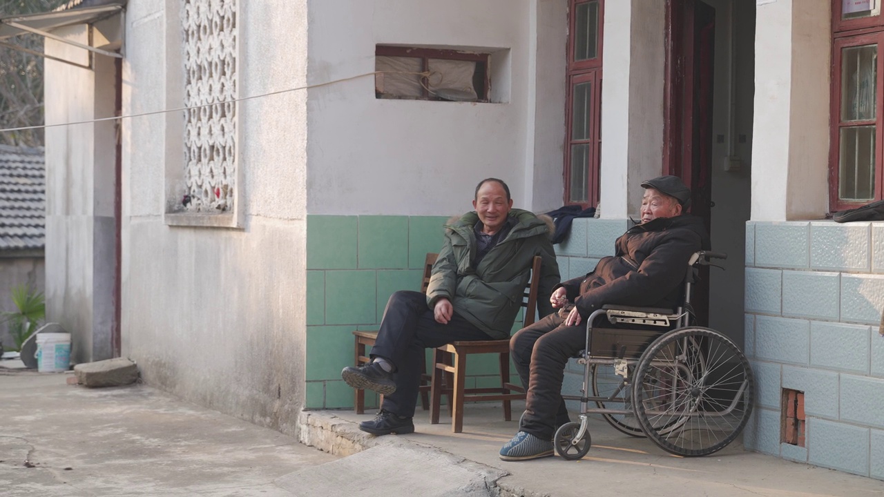 父子俩坐在门口聊天，老父亲坐在轮椅上，老人照护，人口老龄化视频下载