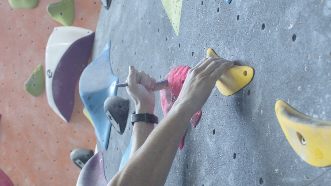 在攀岩馆里，一个攀岩者的手正在清理一个把手视频下载
