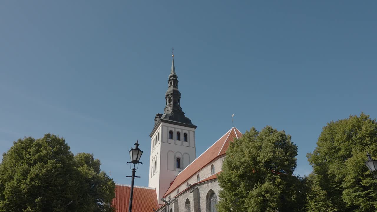 爱沙尼亚塔林，历史悠久的教堂高塔耸立在树梢上，映衬着蓝天视频素材