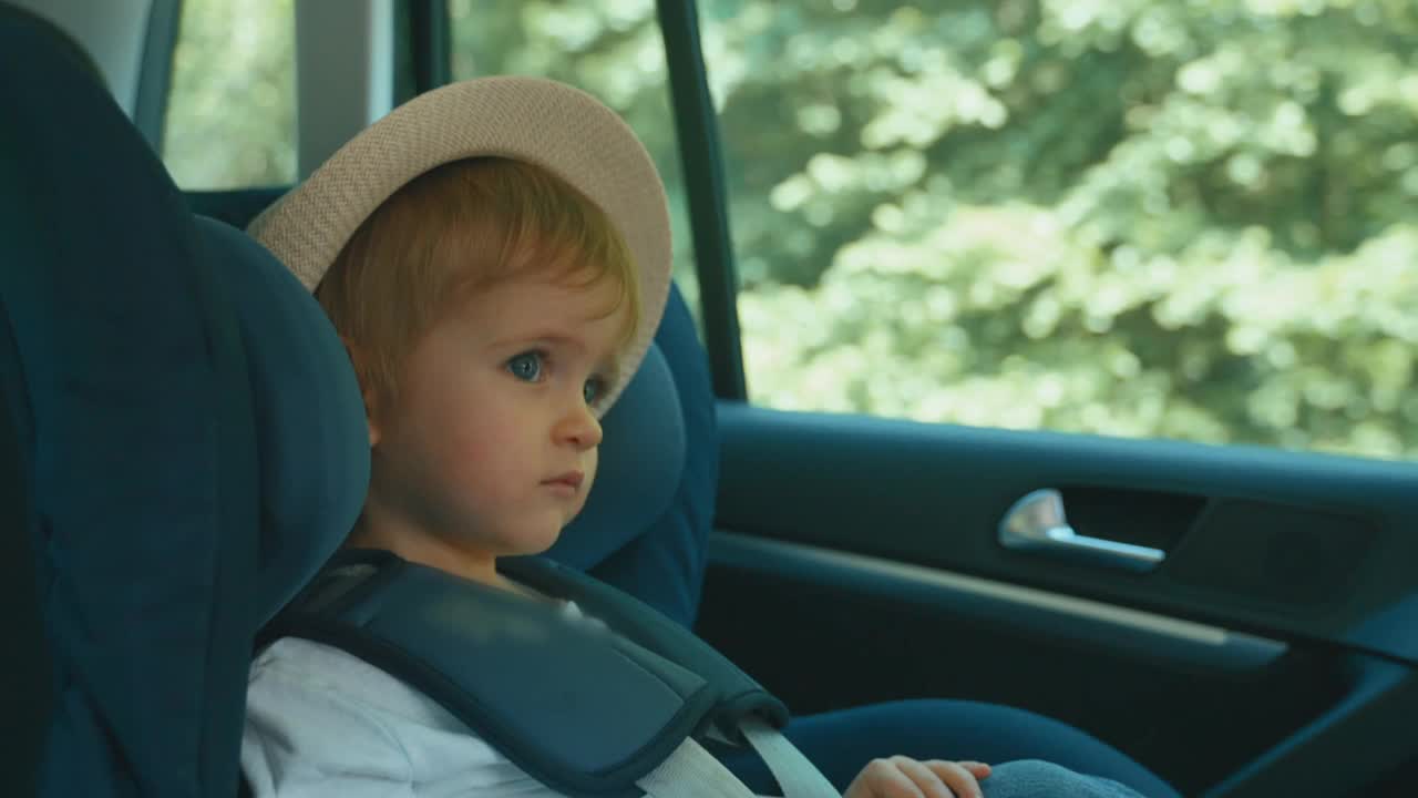 戴着帽子坐在汽车座椅上的小男孩视频下载