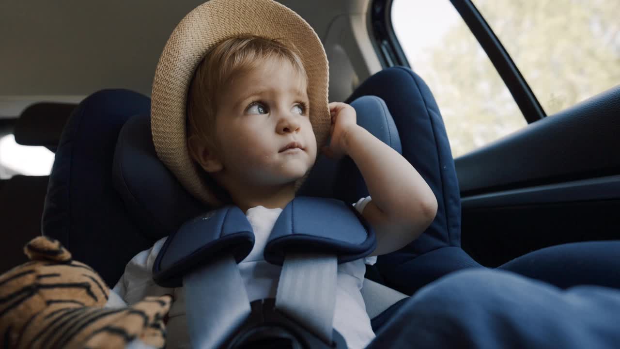 小男孩在汽车座椅上戴着帽子视频素材
