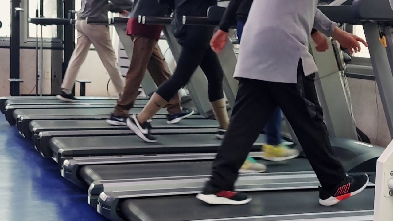 人们在健身房里的跑步机上行走。视频下载