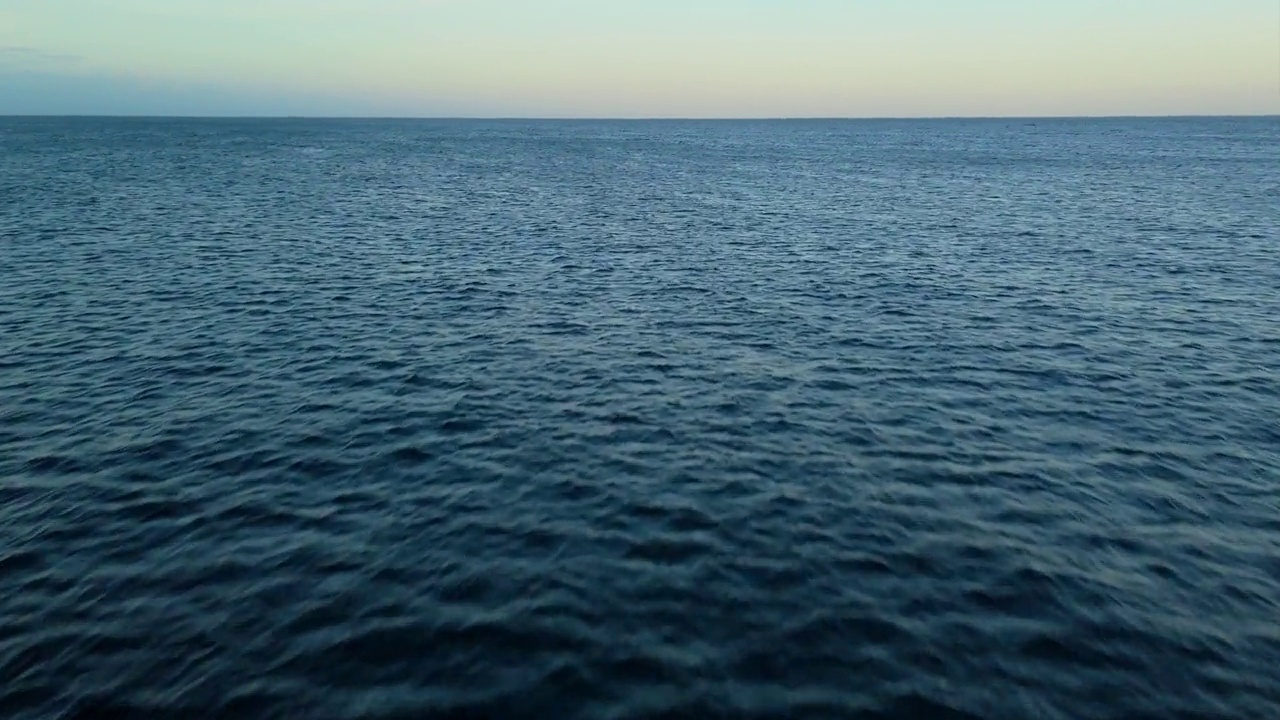 航拍摄影，日落时黑暗的海水与地平线上的金色辉光色调视频下载