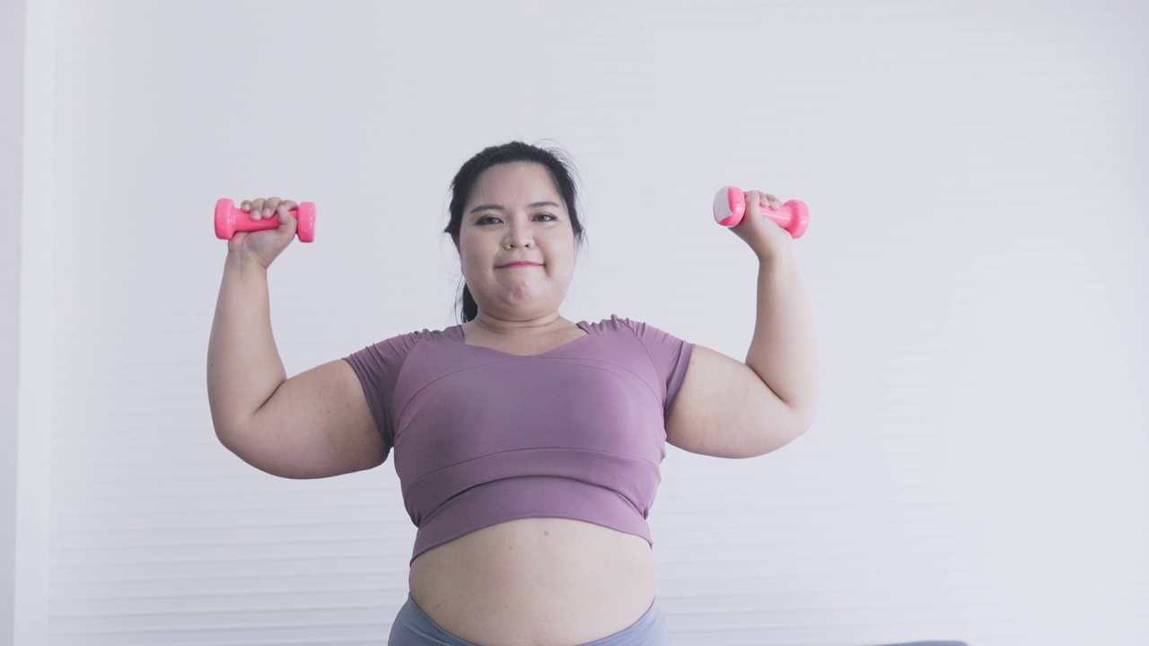 胖乎乎的女人在用哑铃锻炼视频下载