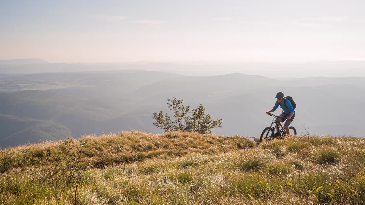 男运动员在山地草地上骑山地自行车视频下载