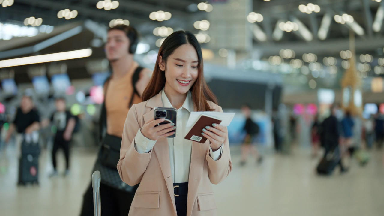 在熙熙攘攘的机场航站楼，年轻的亚洲女商人在手机应用程序上查询航班视频下载