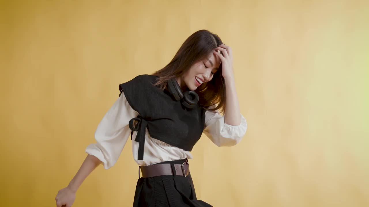 微笑的美丽的亚洲年轻女性的肖像，穿着黑白上衣和黑色短裙，站在孤立的蓝色背景上视频下载