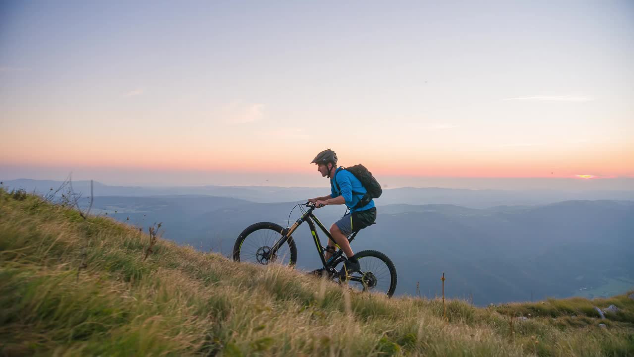 男运动员在日落时分骑越野自行车征服蜿蜒的山路视频下载