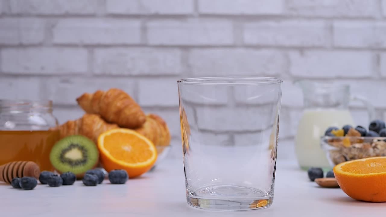 把新鲜的橙汁倒进杯子里当早餐视频下载