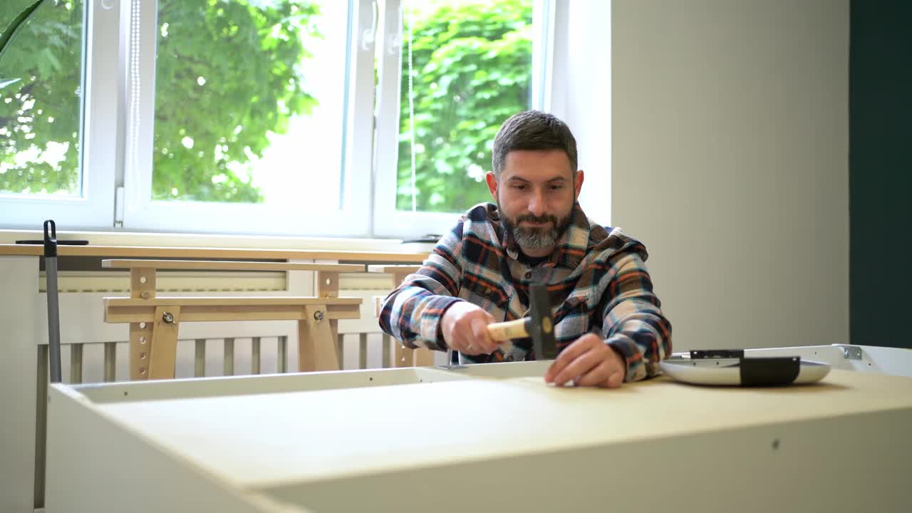 一名白人男子在公寓里组装新家具时使用锤子的视频蒙太奇视频下载