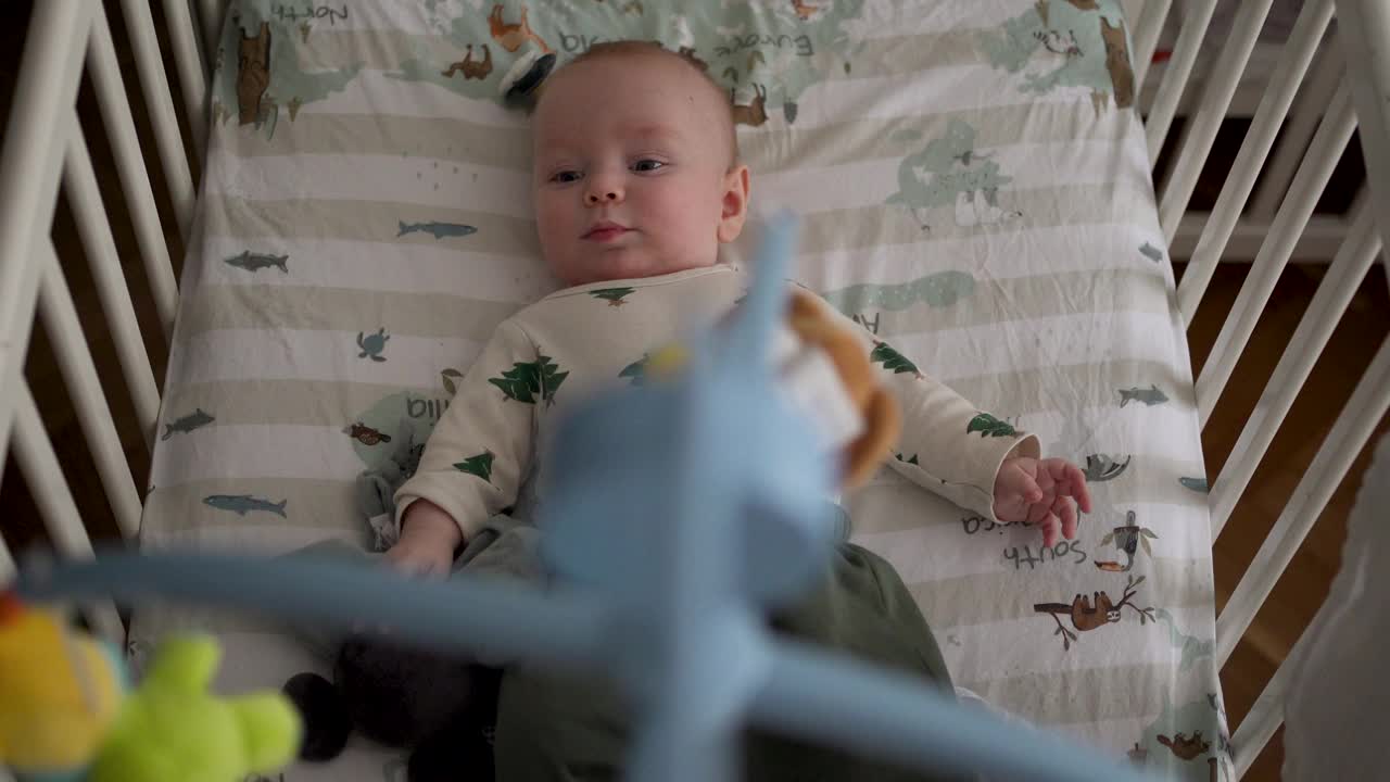 可爱的小男孩在家里的婴儿床上放松视频下载