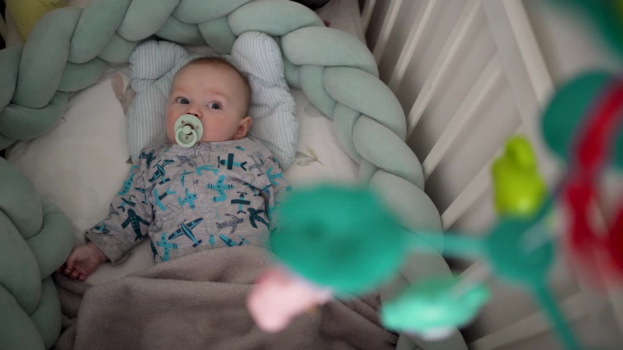 可爱的小男孩在家里的婴儿床上放松视频下载