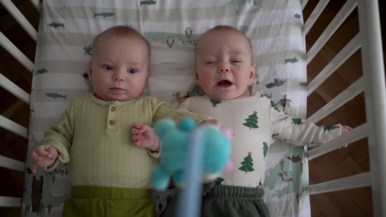 两个可爱的小男孩兄弟姐妹在家里的婴儿床上休息视频下载
