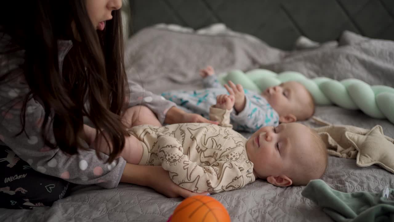 女孩在家里的卧室里和双胞胎男婴玩耍视频下载