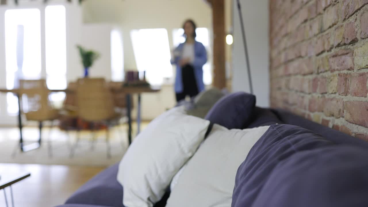 年轻的孕妇躺在沙发上，在家里喝咖啡视频下载
